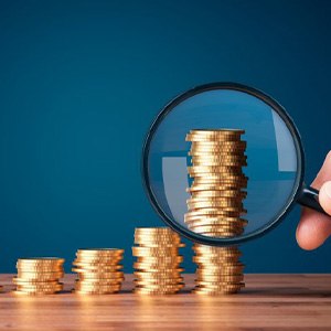 Magnifying glass inspecting increasingly taller stacks of coins