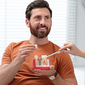 Dentist showing patient a dental mold with a single implant