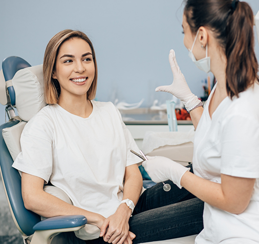 Female patient sitting in dental chair and smiling at dentist in Georgetown