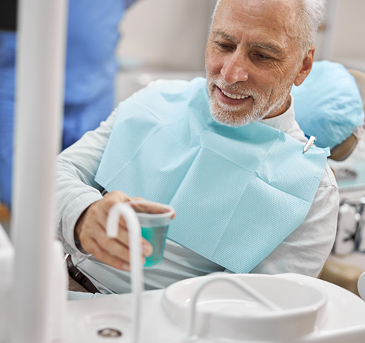 Male dental patient about to pour liquid into sink