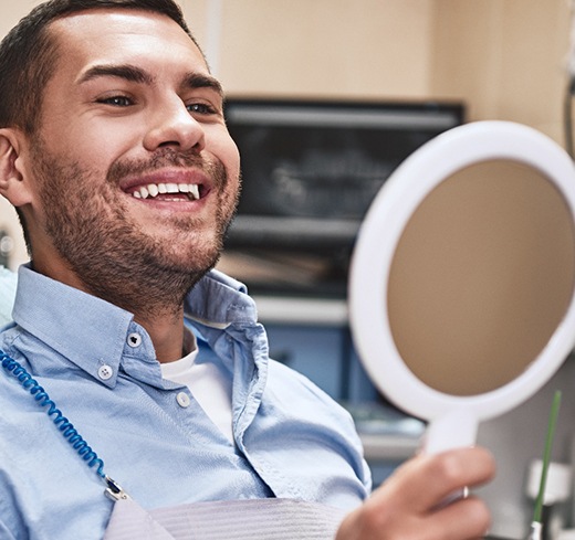 Man smiling with a hand-held mirror