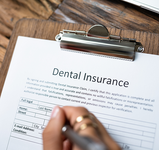 Filling out dental insurance form on clipboard