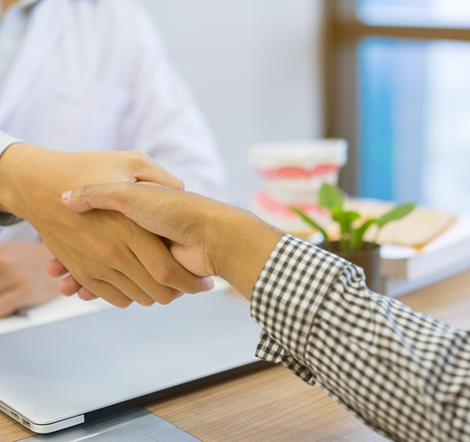 Shaking hands over desk with laptop
