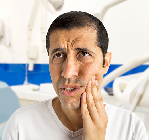 Man in white shirt rubbing his jaw in pain