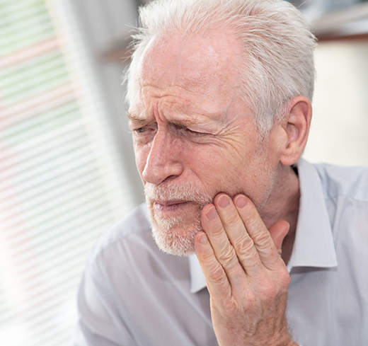 Older man rubbing his jaw in pain