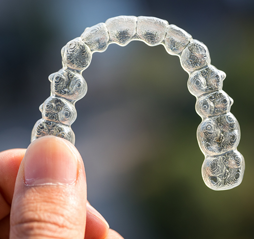 Hand holding Invisalign clear aligner